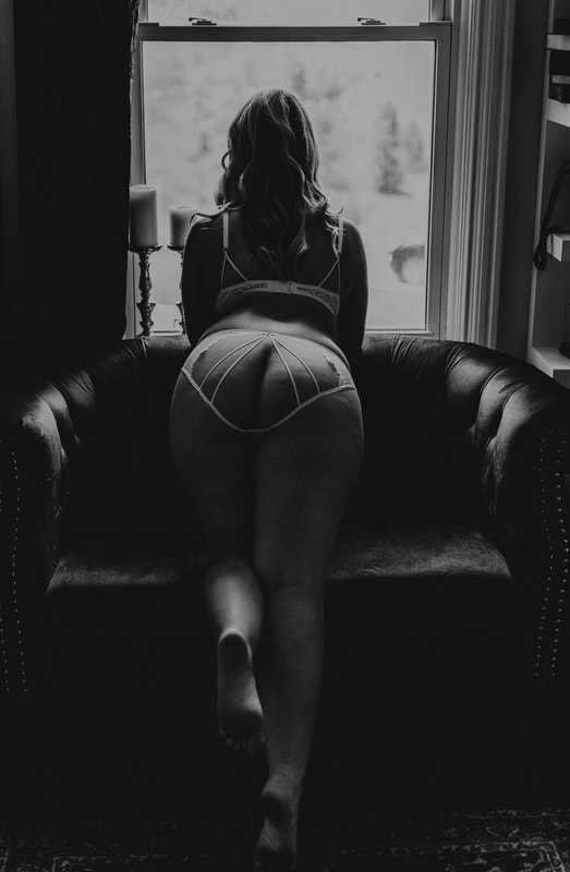 Boudoir photo of woman leaning over couch.